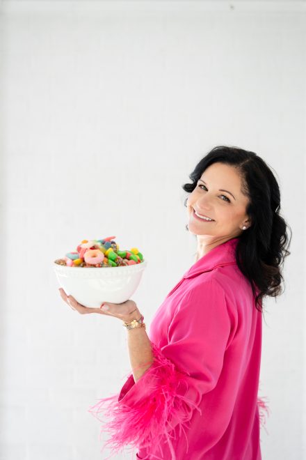 Playful female entrepreneur surrounded by colorful candies in a bright Vancouver studio, showcasing her vibrant candy brand.