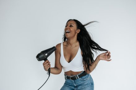 Close-up shot of a hair stylist confidently gripping styling tools in a Lower Mainland studio, surrounded by brushes and products to emphasize her craft.