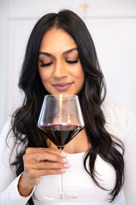 Confident dietitian standing in a well-lit kitchen in Fraser Valley, ready to guide clients on their wellness journey and showing balance is key with glass of wine