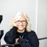 Confident female personal trainer smiling warmly in a bright home studio in Langley, showcasing her professionalism and approachability.