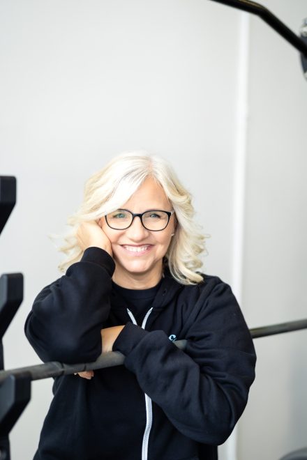 Confident female personal trainer smiling warmly in a bright home studio in Langley, showcasing her professionalism and approachability.