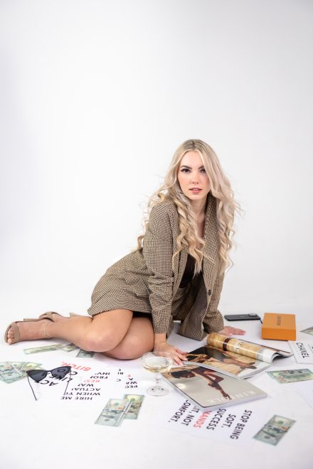Candid branding photo of Demi sitting on the floor surrounded by marketing materials under dramatic, moody lighting