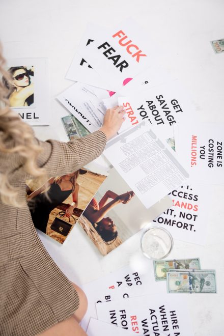 Candid branding photo of Demi sitting on the floor surrounded by marketing materials under dramatic, moody lighting