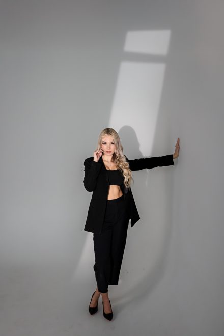 Dramatic studio headshot of Demi posing against a crisp white backdrop with high-contrast lighting in Port Coquitlam
