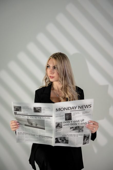 Female SEO posing while holding a newspaper with creative light