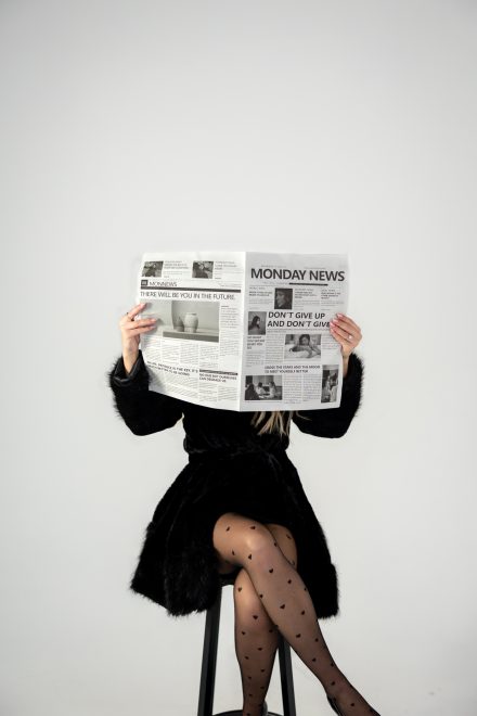 Female SEO posing while holding a newspaper with creative light