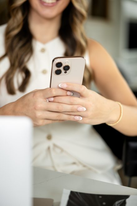 Female realtor in Langley texting on her phone while leaning against a white marble kitchen island