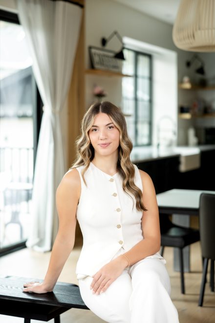 Professional headshot of a female realtor standing in a bright, modern home entrance in Langley, BC